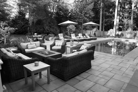 Backyard pool with paver patio, lounge seating, and a fire-pit table by Alderwood Landscaping